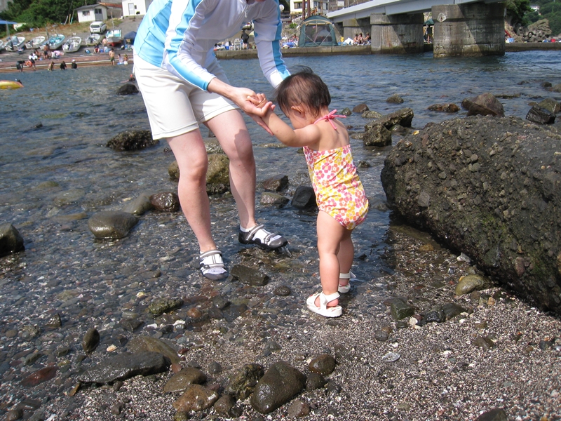 海を歩く子供と手を持つ大人